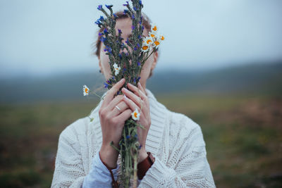 Midsection of woman holding flower on field