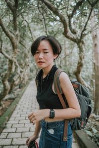 Portrait of young woman standing on footpath