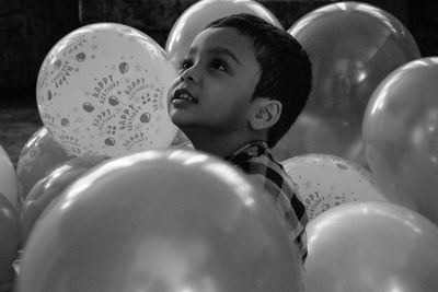 Close-up of cute boy sitting amidst balloons