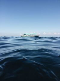 Boat sailing on sea at distant against sky