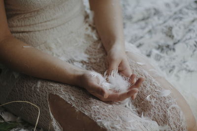 Midsection of woman holding feathers