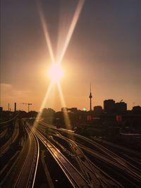 Railroad tracks in city against sky during sunset