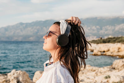 Portrait of woman wearing sunglasses standing at beach