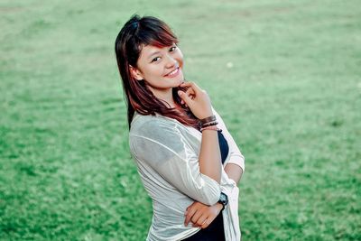 Portrait of smiling young woman standing on grass