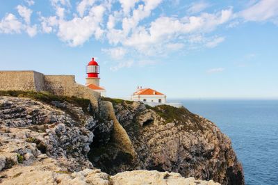 Lighthouse by sea against buildings