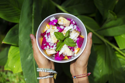 Woman's hands holding bowl of tropical fruit salad