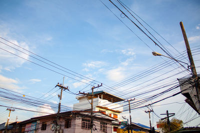 Low angle view of electricity pylon and buildings against sky