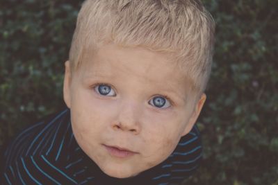 Close-up high angle portrait of cute baby boy with messy face and gray eyes outdoors