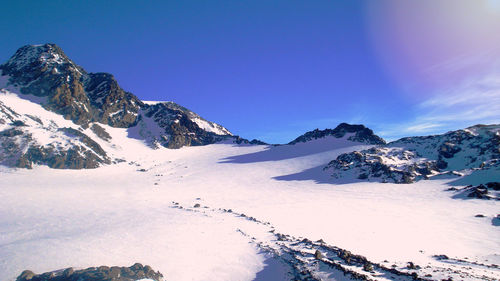 Scenic view of snowcapped mountains against blue sky