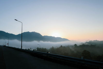 Road by street against sky during sunset