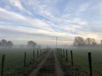 Wooden fence on field against sky