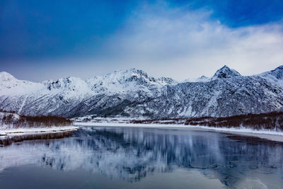 Scenic view of snowcapped mountains by lake against sky during winter