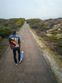 A man with long hair skating on a empty road in europe