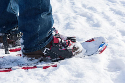 Low section of person wearing snowshoe in snow