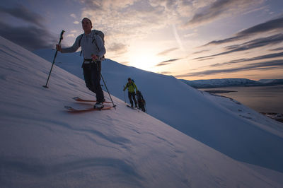 Group of people backcountry skiing at sunrise in iceland