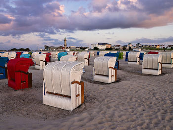 Hooded chairs on beach against sky