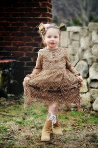 Portrait of cute girl wearing dress while standing on field