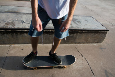 Low section of man with skateboard on footpath