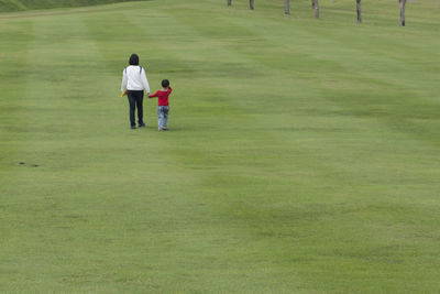 Mother and son walking on grassy field