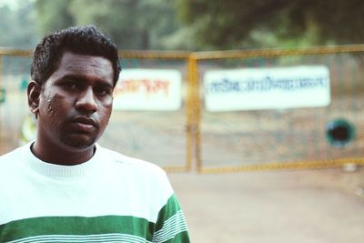 Portrait of young man standing against gate