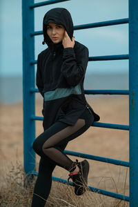 Portrait of young woman sitting on railing