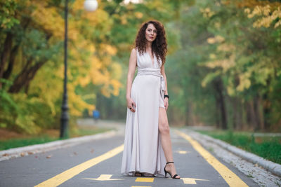 Woman standing on road against trees