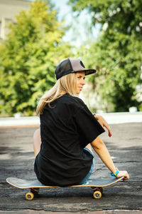 Rear view of woman sitting on skateboard