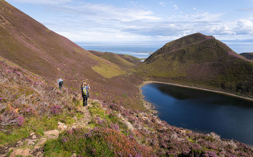 Rear view of girl and man walking on a hiking trail on the isle of skye, scotland