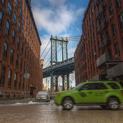 Cars on bridge in city against sky