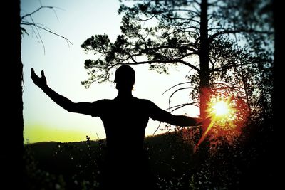 Silhouette man standing by tree against sky during sunset