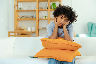 Portrait of young woman sitting on bed at home