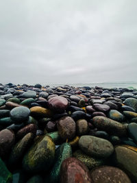 Stones in sea against sky