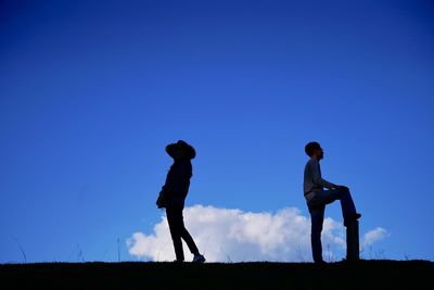Silhouette people standing on field against clear blue sky