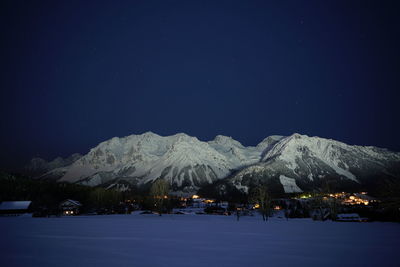 Snowcapped mountains against clear blue sky at night