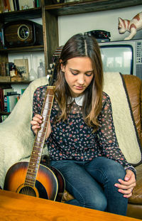 Young woman playing guitar at home