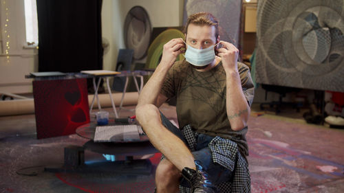 Full length portrait of young man sitting at home