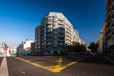 View of city street and buildings against blue sky