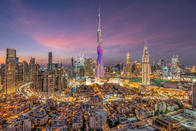 Illuminated modern buildings in city against sky