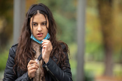 A beautiful girl in a medical protective mask is going to swallow pills for colds and flu. 