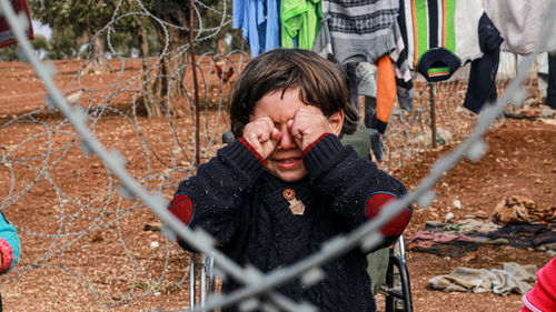 Portrait of boy standing by chainlink fence