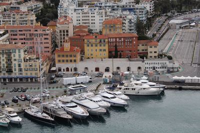 High angle view of boats moored at harbor by buildings in city