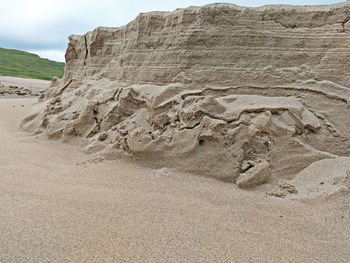 Sand dune on beach against sky