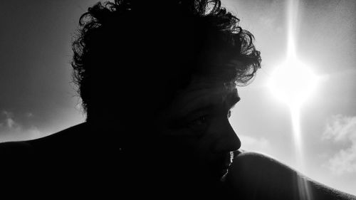 Low angle view of sun shining through clouds