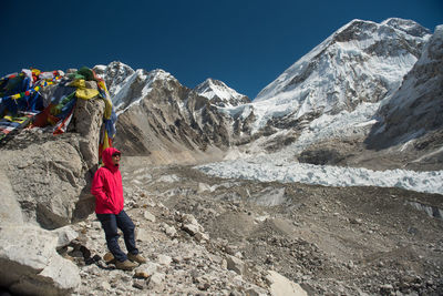 Woman standing on rocks by mountain against sky