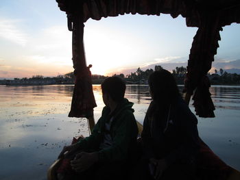 Rear view of silhouette people looking at sea during sunset