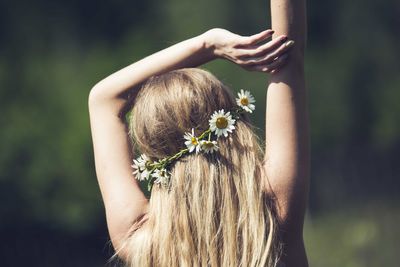 Rear view of woman wearing flowers on hair during sunny day