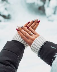 Cropped hands of woman showing painted fingernails during winter
