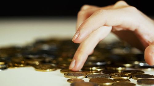 Cropped hand of woman with coins on table
