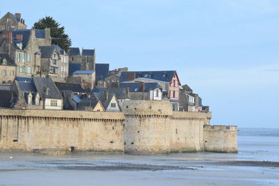 Buildings by sea against sky