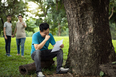 Men sitting on tree trunk against plants